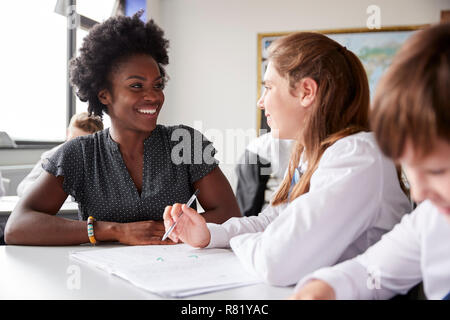 High School Lehrer geben Weibliche Student trägt Uniform Einzelunterricht am Schreibtisch Stockfoto