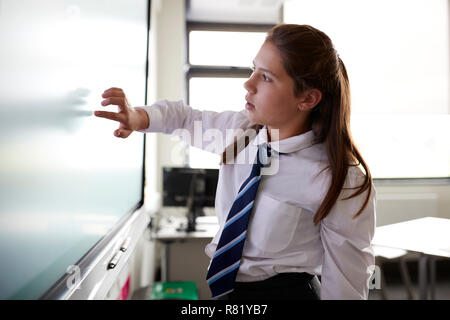 Weibliche High School Student trägt die einheitliche Verwendung der interaktiven Whiteboard während der Lektion Stockfoto