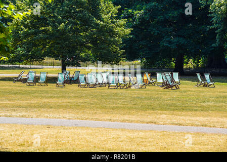 Leere Liegestühle in St James's Park, London, Großbritannien. Sonniger Tag im Sommer mit braunem Gras. Keine Kunden für kostenpflichtige Sitzplätze Stockfoto