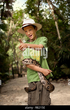 Fröhlicher junger Boy mit einer Schlange um den Körper gewickelt. Stockfoto