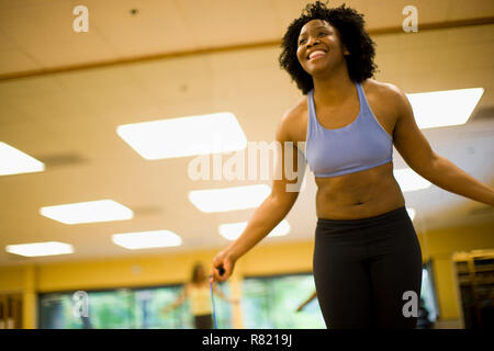 Lächelnden jungen Frau springen mit einem Springseil in einem Fitnessstudio. Stockfoto