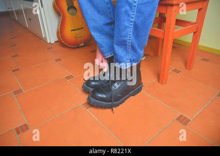 Rock und Roll Konzept. Schwarze Stiefel und akustischer Gitarre. Das Setzen auf Rock und Roll Stiefel Stockfoto