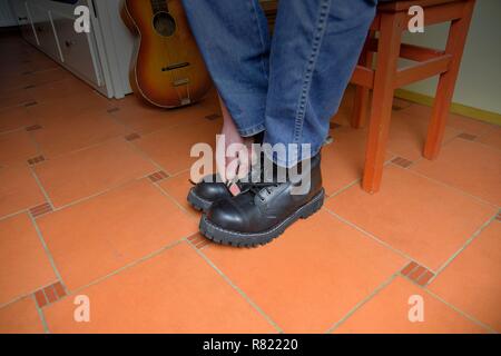 Rock und Roll Konzept. Schwarze Stiefel und akustischer Gitarre. Das Setzen auf Rock und Roll Stiefel Stockfoto