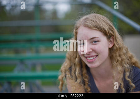 Lächelnde Frau sitzt auf der Tribüne am Sportplatz Stockfoto
