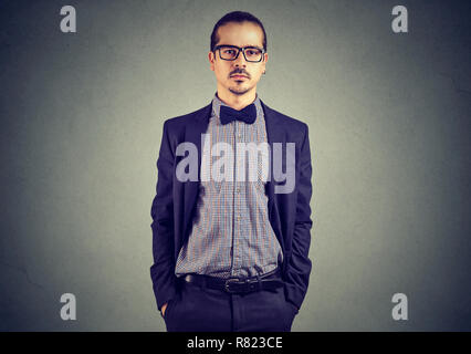 Hübscher junger Mann mit modischen Anzug und Brille, Hände in den Taschen und Kamera Stockfoto