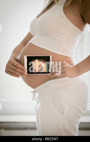 Frau in ihrem neunten Monat schwanger, hält Foto des Fötus im Bauch, Ultraschall Bild, Deutschland Stockfoto