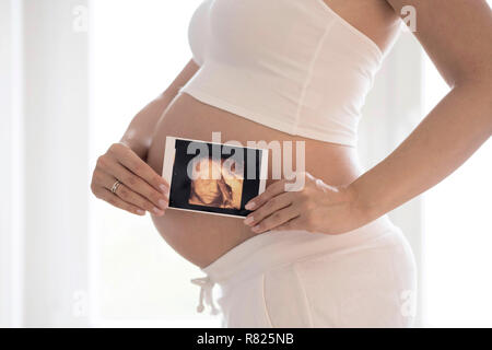 Frau in ihrem neunten Monat schwanger, hält Foto des Fötus im Bauch, Ultraschall Bild, Deutschland Stockfoto