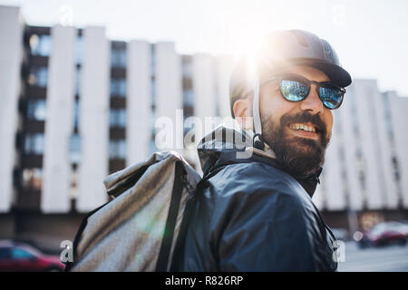 Männliche Kurier mit Sonnenbrille die Auslieferung von Paketen in der Stadt. Stockfoto