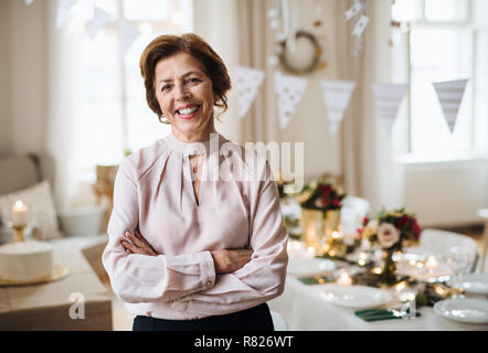 Das Porträt einer älteren Frau, die Zuhause in einem Zimmer für eine Partei. Stockfoto