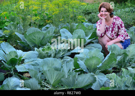 Frau sitzt auf der Kohl Feld im Sommer Stockfoto