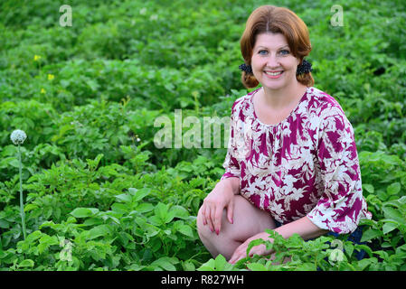 Frau sitzt auf der Kartoffelfeld im Sommer Stockfoto