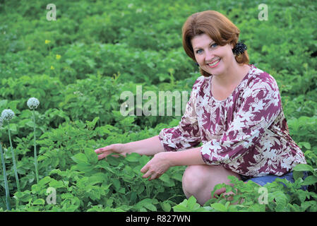 Frau sitzt auf der Kartoffelfeld im Sommer Stockfoto