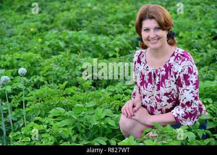 Frau sitzt auf der Kartoffelfeld im Sommer Stockfoto