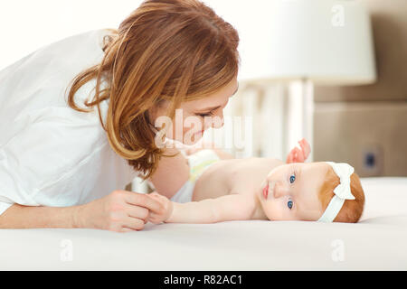 Eine glückliche Großmutter mit Baby Enkel auf dem Bett. Stockfoto