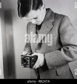 1950, historische, eine englische Schüler in einer Wolljacke mit einem Metallgehäuse Kodak "Brownie"-Modell E Sechs-20 Film Kamera, einem beliebten-Kamera der Ära, in der Egge in England, die zwischen 1953-1957. Stockfoto