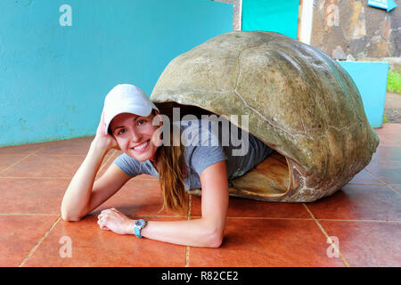 Junge Frau im inneren Leere Galapagos Riesenschildkröte Shell im Heiligtum liegen auf Santa Cruz Island, Galapagos, Ecuador. Stockfoto