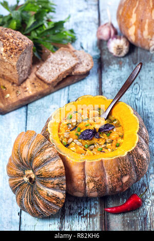 Suppe mit Linsen in den geschnitzten Kürbis auf dem blauen Hintergrund Holz dekoriert im Herbst Urlaub Stockfoto