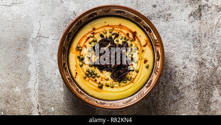 Banner der authentischen griechischen Fava Rezept, im Nahen und Mittleren Osten gelbe Linsensuppe mit karamellisierten Zwiebeln, Paprika und Kapern. vegan gesunde Lebensmittel in Tontöpfen Stockfoto