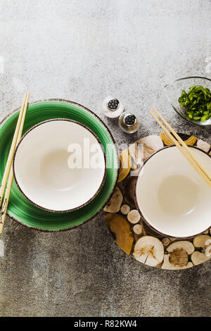 Leere Schüsseln auf den Tisch und Chinesischen Stäbchen. Die Tabelle ist im japanischen Stil eingerichtet. auf einem Tisch aus Stein Stockfoto