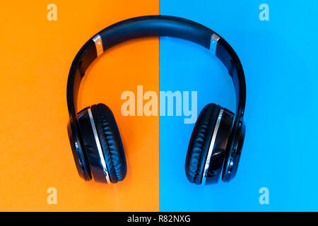 Schwarz kabellose Kopfhörer auf einem geteilten orange und blau hintergrund Stockfoto