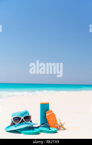 Sonnencreme-Flaschen, Schutzbrille, Seesterne und Sonnenbrille auf weißem sand Strand Hintergrund Ozean Stockfoto