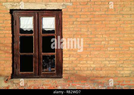 Dunkel Braun Holz- Fenster auf Terrakotta gemauerte Wand im Sonnenlicht Stockfoto