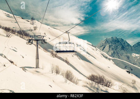 Sesselbahn Lifte Skifahrer und Snowboarder auf den Gipfel des Berges, in der Nähe des Dorfes Dombai, Russland in einem Winter sonniger Tag. Getonten Bild Stockfoto