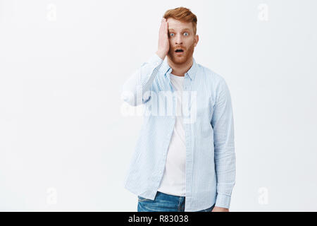 Mann verloren Speicher war schockiert, und in Erstarrung, keine Idee, was sie als nächstes tun. Portrait von Devestated betäubt Reife rothaarige Mann im Hemd, holding Palm auf Gesicht und Kiefer aus schüttelte Stockfoto