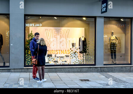 Ein junges Paar in Rennes, Frankreich steht vor einem Schaufenster Display mit der Angabe "Sehr Frohe Weihnachten' im Dezember. Stockfoto