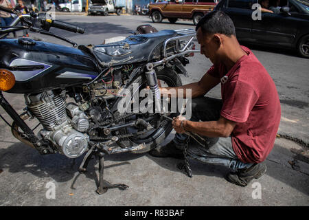 Caracas, Venezuela. 11 Dez, 2018. Eine venezuelanische Reparaturen der Reifen eines Motorrades. Angesichts der Wirtschaftskrise, alles, was in Venezuela wird repariert, bis es vollkommen nutzlos ist. Die venezolanische Inland leidet unter der Wirtschaftskrise. Nach Angaben des Internationalen Währungsfonds (IWF), der Südamerikanischen Land ist die Überschrift für die Inflationsrate von 1,37 Millionen Prozent im Jahr 2018. Credit: Rayner Pena/dpa/Alamy leben Nachrichten Stockfoto