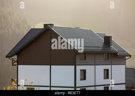 Neue schöne weiße und braune zweistöckiges Ferienhaus mit Schindeldach im ökologischen Bereich auf nebligen Wald und Hügel Hintergrund auf sonnigen Sommertag. Auch maintai Stockfoto