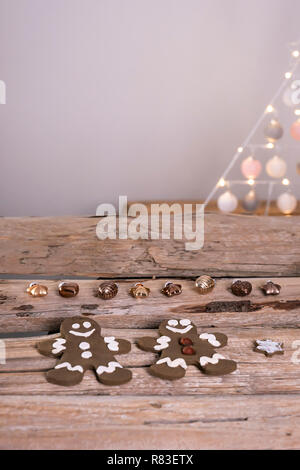 Lebkuchen Männer liegen mit Bronze farbigen Weihnachtsbaum Anhänger auf alten Holzbalken. Stockfoto
