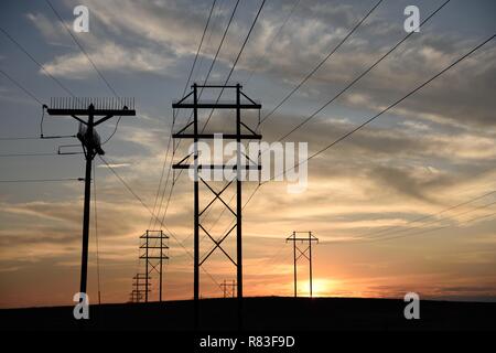 Silhouette des Stromnetzverteilernetzes, Strommasten und Hochspannungsleitungen, die bei Sonnenuntergang in den fernen Horizont übergehen Stockfoto