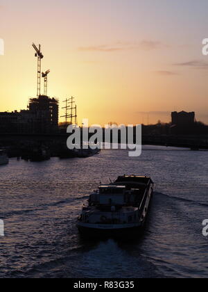 Bremen, Deutschland - Dezember 11th, 2018 - Frachtschiff auf der Weser bei Sonnenaufgang mit Baustelle und Krane in der Ferne Stockfoto