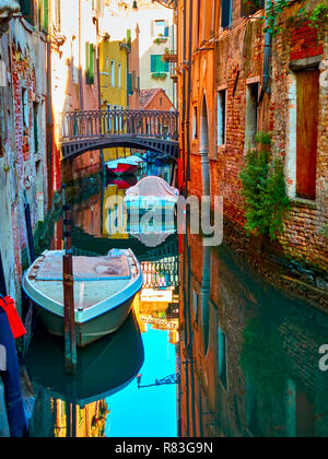 Schattig Kanal mit kleinen Brücke und Motorboote in Veinice, Italien Stockfoto