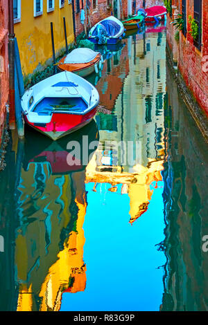 Kleinen Kanal mit angelegten Motorboote in Veinice und Reflexionen im Wasser spiegeln, Italien. Venezianische Stadtbild Stockfoto