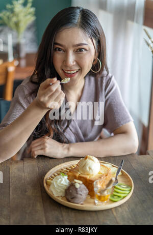 Frau essen Honig Toast, süße Nachspeise im Cafe Stockfoto