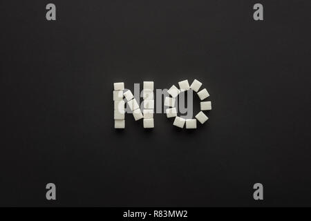 Draufsicht auf das Wort "Nein" aus Würfelzucker isoliert auf Schwarz Stockfoto