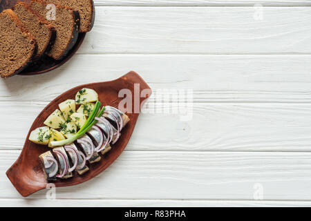 Marinierter Hering mit Kartoffeln und Zwiebeln aus Steingut Teller mit Roggenbrot und kopieren Raum auf weißem Holz- Hintergrund Stockfoto