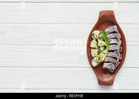 Lecker marinierten Hering mit Kartoffeln und Zwiebeln aus Steingut Teller auf weißem Holz- Hintergrund mit Kopie Raum Stockfoto