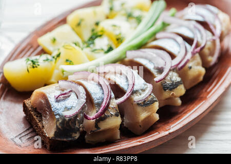 Nahaufnahme der Lecker marinierten Hering mit Kartoffeln und Zwiebeln aus Steingut Teller Stockfoto