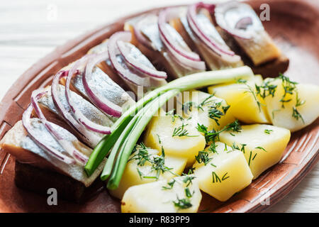 Nahaufnahme der Lecker marinierten Hering mit Kartoffeln und Zwiebeln aus Steingut Teller Stockfoto