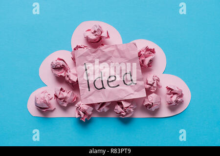 Blick von oben auf die rosa Karton cloud mit zerknittertem Papier Kugeln und 'Idee' Wort auf Haftnotiz auf blauem Hintergrund geschrieben, Ideen Konzept Stockfoto