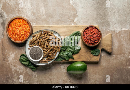 Ansicht von oben gesundes Müsli, Goji Beeren, rote Linsen und Spinat auf Holzbrett mit rustikalen Hintergrund Stockfoto