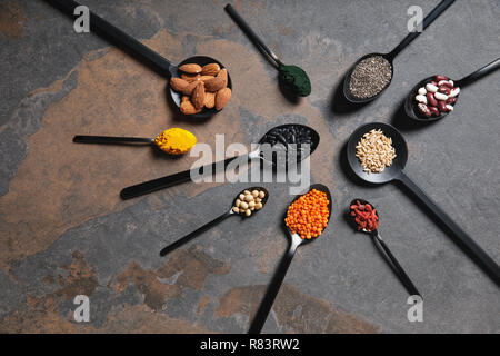 Flach der Löffel mit Superfoods, Hülsenfrüchte und Körner am Tisch Stockfoto