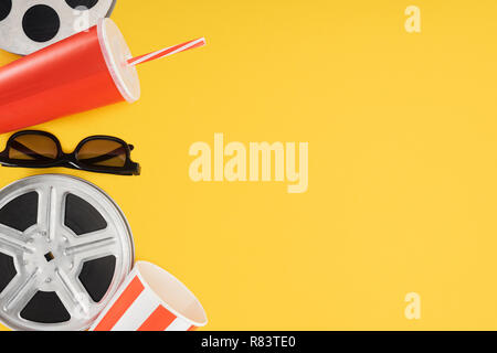 Filmrollen, 3D-Brillen, Popcorn Schaufel und rot Einweg Becher mit Stroh isoliert auf Gelb Stockfoto
