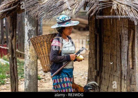 Thakhek, Laos - April 20, 2018: Weiblich Landwirt mit einem Holz- Korb vor einer Hütte in einem ländlichen Dorf im südlichen Laos Stockfoto