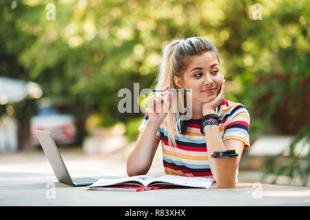 Bild eines Denkens nachdenkliche junge süße Mädchen student sitzt im Park mit Laptop Computer schreiben. Stockfoto