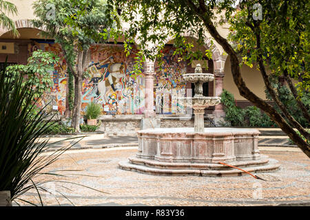 Innenhof mit Springbrunnen am Instituto Allende in San Miguel de Allende, Mexiko. Die Wandmalereien in den Hintergrund ist vom legendären mexikanischen Wandmaler David Alfaro Siqueiros. Stockfoto