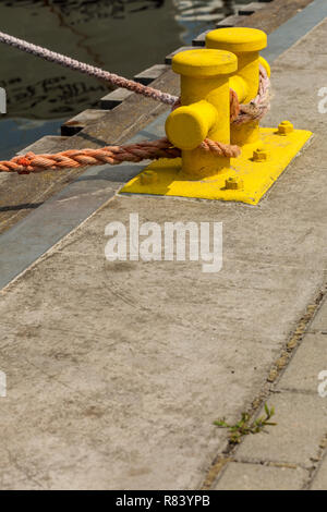 Liefer- objekte Konzept. Segeln Seile gebunden um Gelbe marina Pins. Außenaufnahme an einem sonnigen Tag. Stockfoto